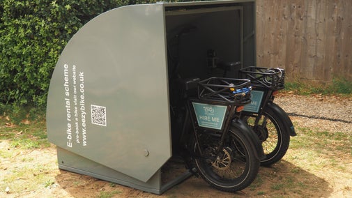 An electric bike charging pod open showing bike tyres on display